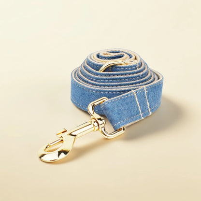 Blue denim dog lead with gold hardware on a beige background