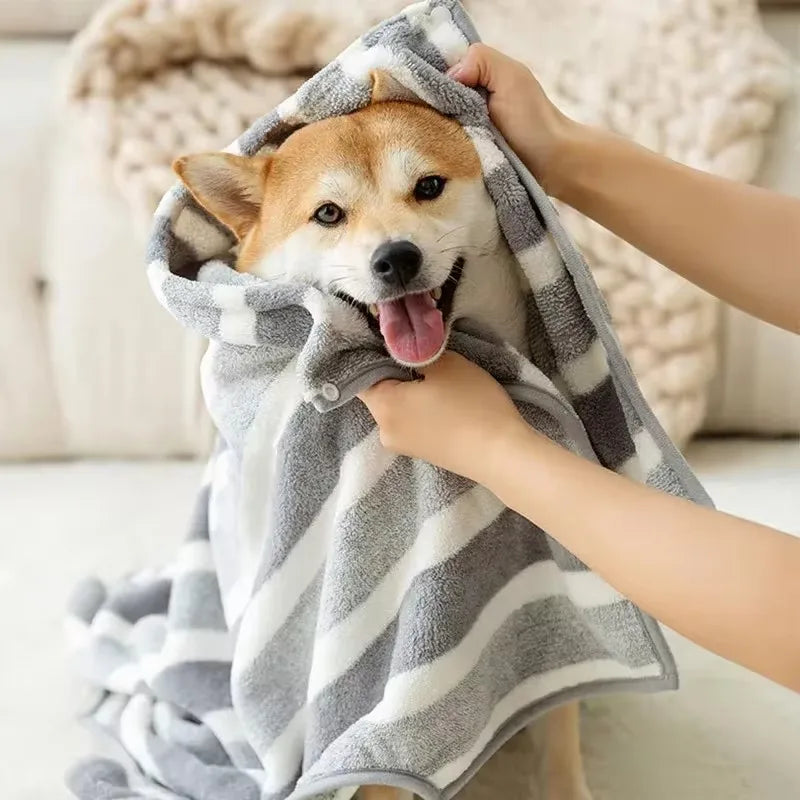 Dog wrapped in a fleece drying robe with grey and white stripes, ensuring warmth and dryness.