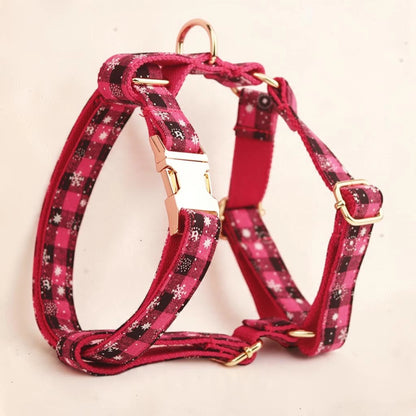 A pink plaid dog harness with white snowflake patterns and gold-tone metal hardware. Buckle can be personalised.