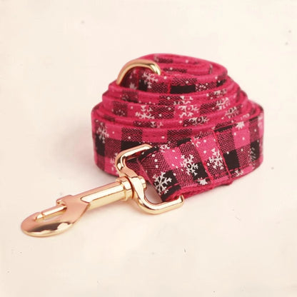 A pink plaid dog lead with white snowflake patterns and a gold-tone metal clasp.