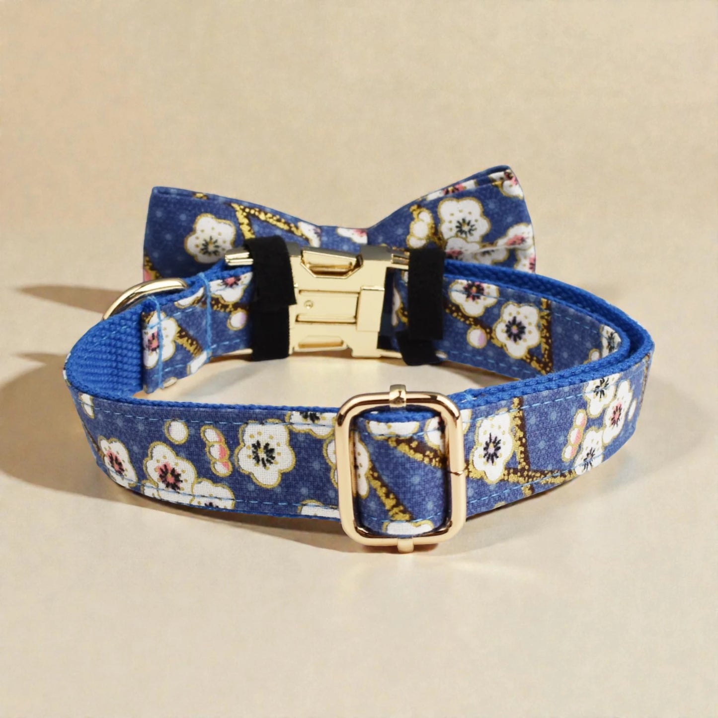 Blue floral-patterned dog collar with gold buckle on a beige background