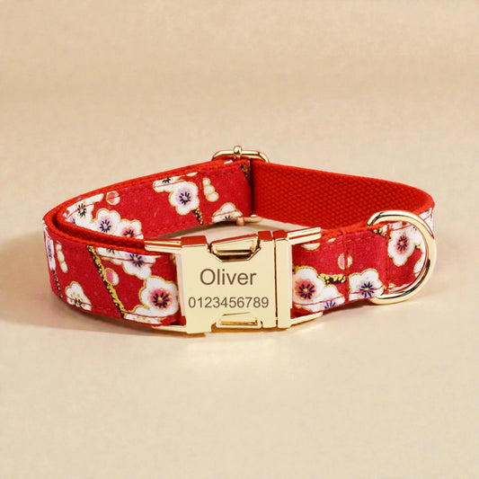 Red floral dog collar with gold buckle and engraved nameplate on a beige background