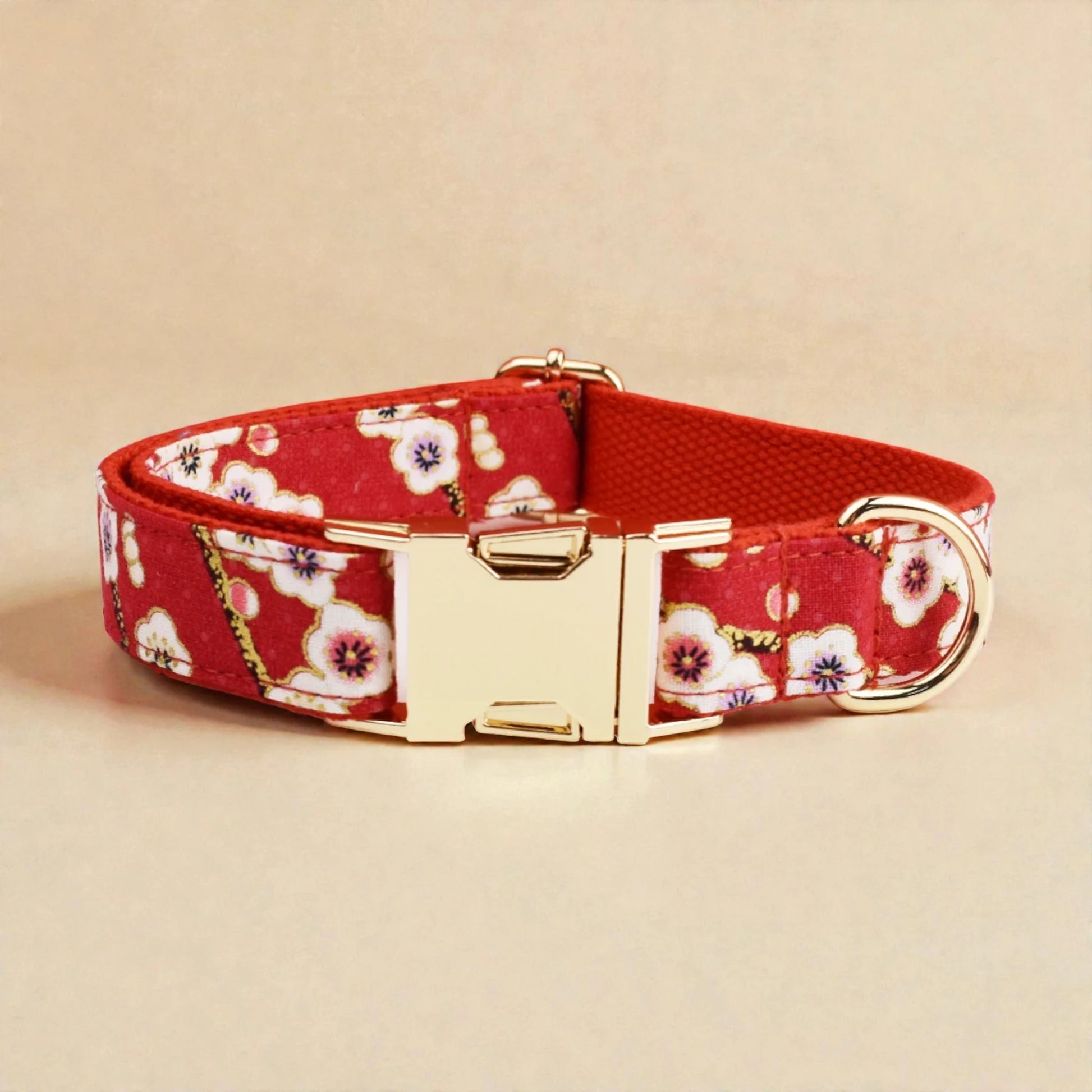 Red floral dog collar with gold buckle on a beige background