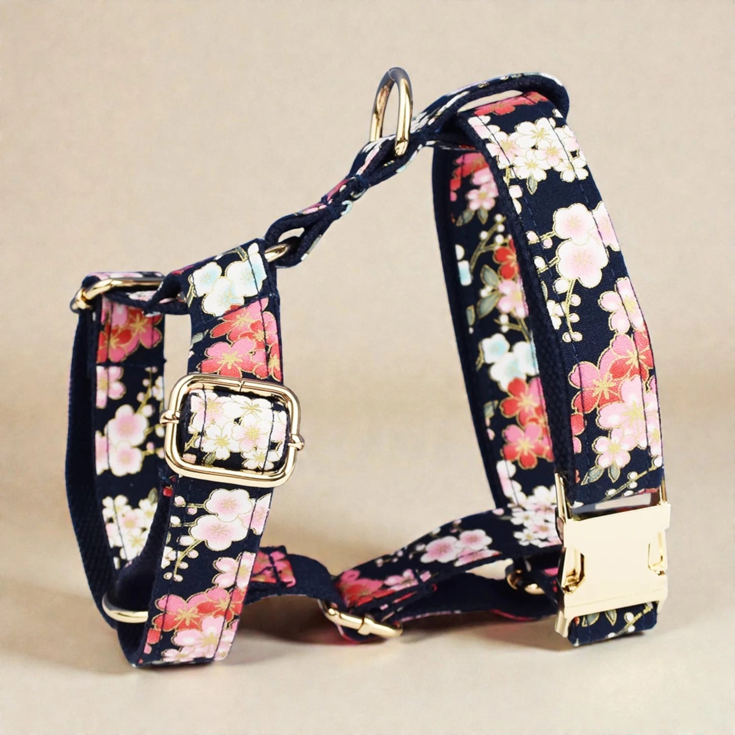 Floral-patterned dog harness with gold hardware on a beige background