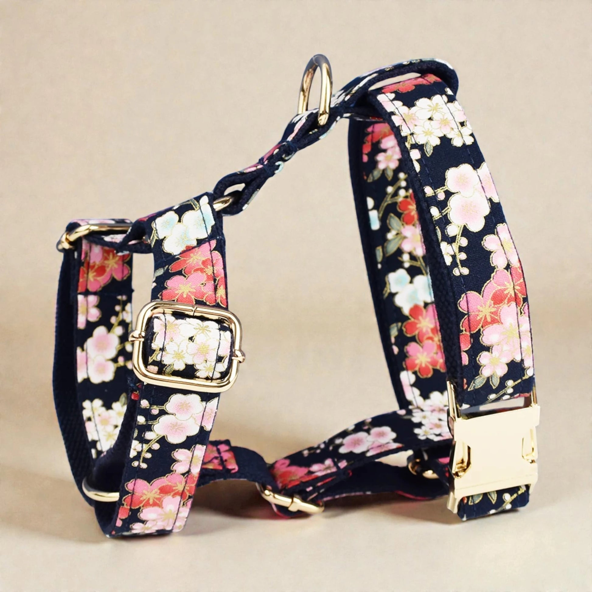 Floral-patterned dog harness with gold hardware on a beige background