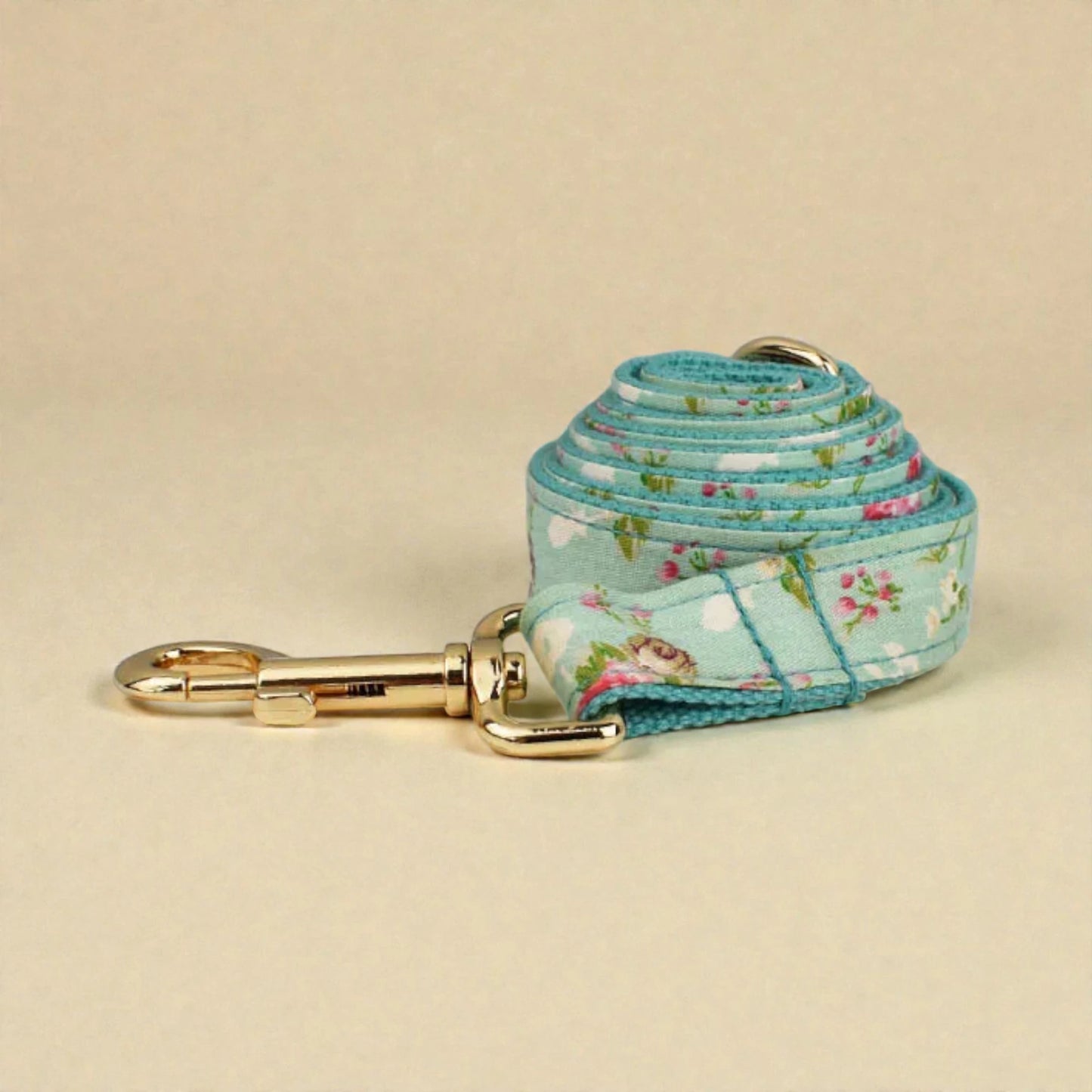 Floral-patterned dog leash with gold clip on a beige background