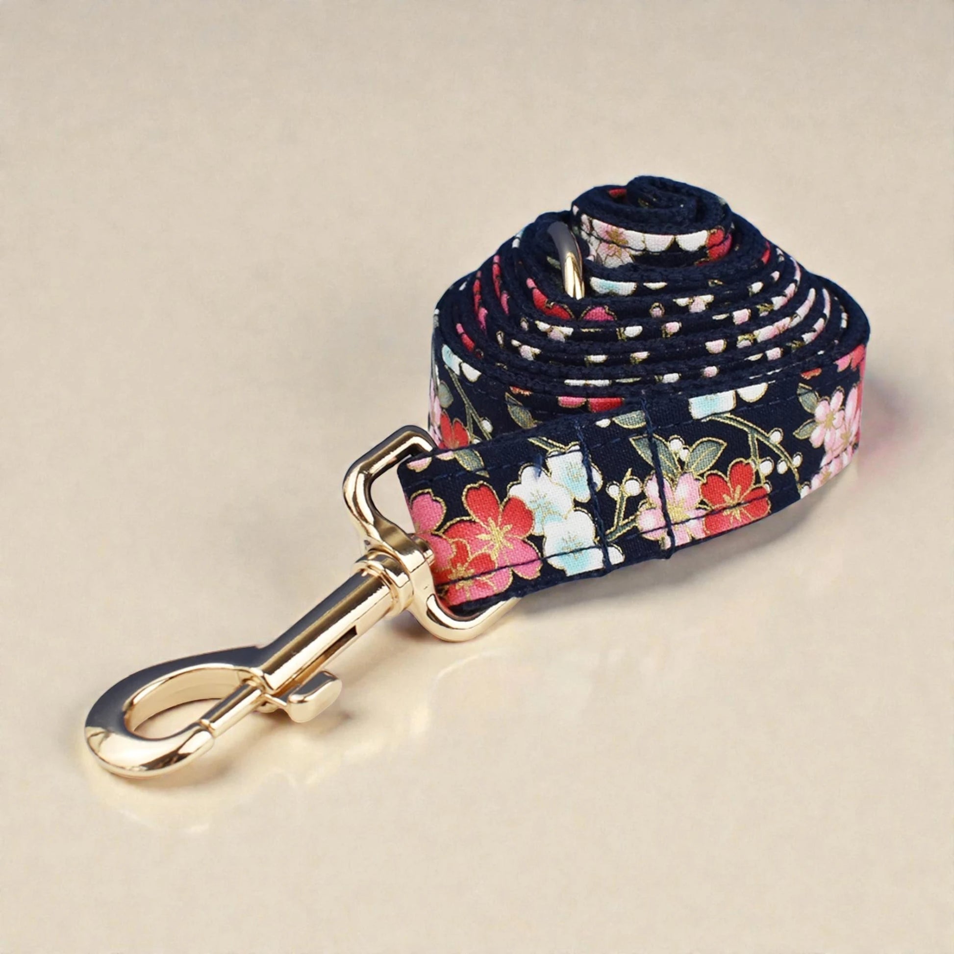 Floral patterned dog leash with a gold clip on a beige background