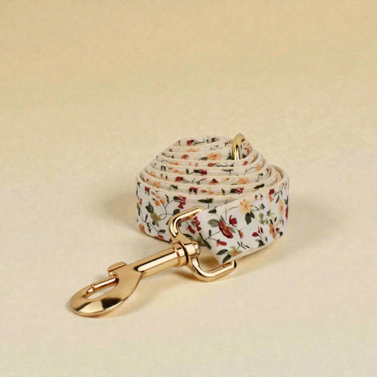 Floral-patterned dog lead with gold clip on a beige background