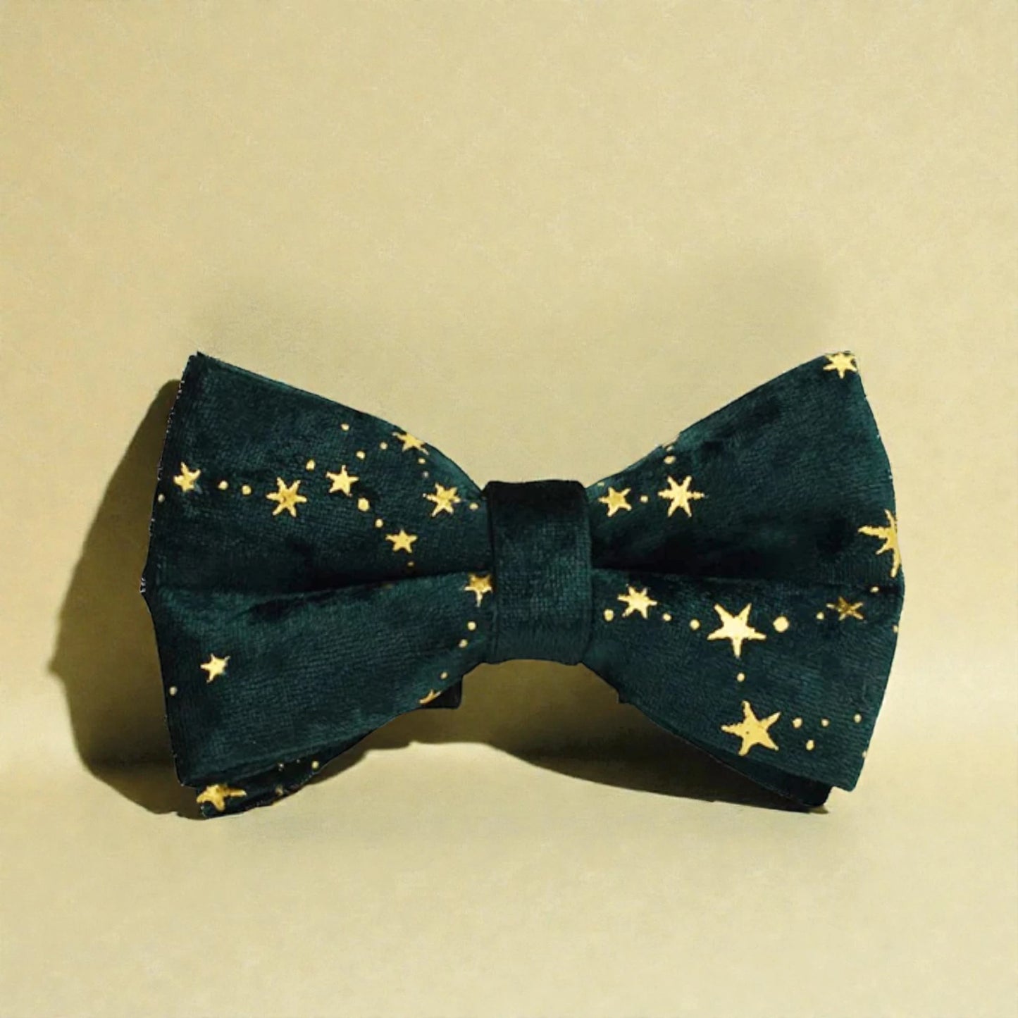 Green bow tie with gold star pattern on a beige background