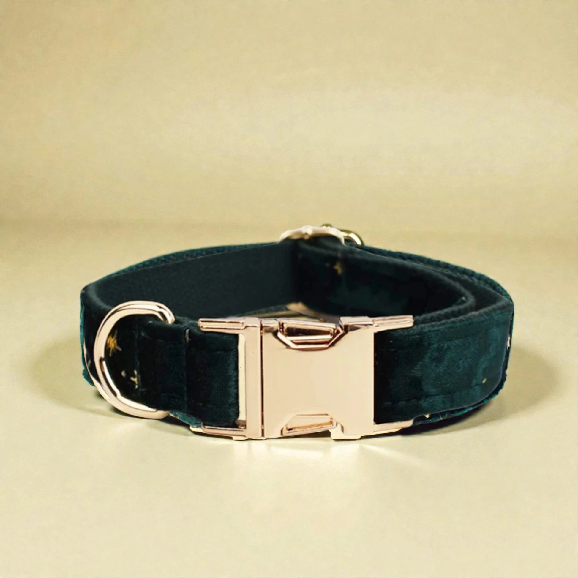 Green velvet dog collar with a gold buckle on a beige background