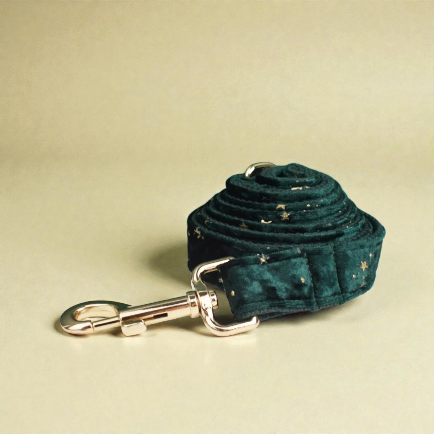Green velvet dog lead with gold clip on a beige background
