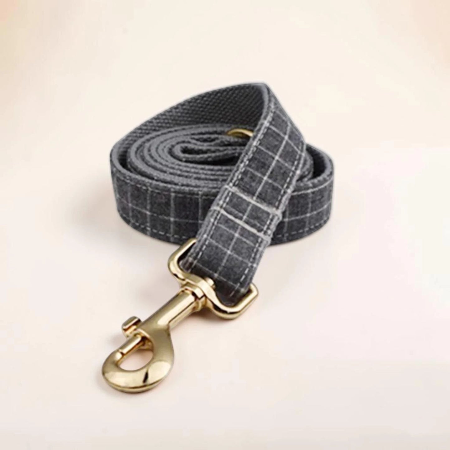 A grey check dog lead with a gold clip.