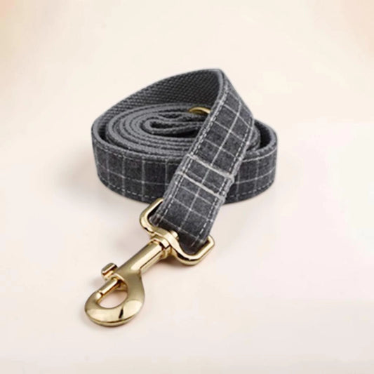 A grey check dog lead with a gold clip.