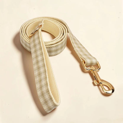 A beige heritage check dog lead with a gold clasp.