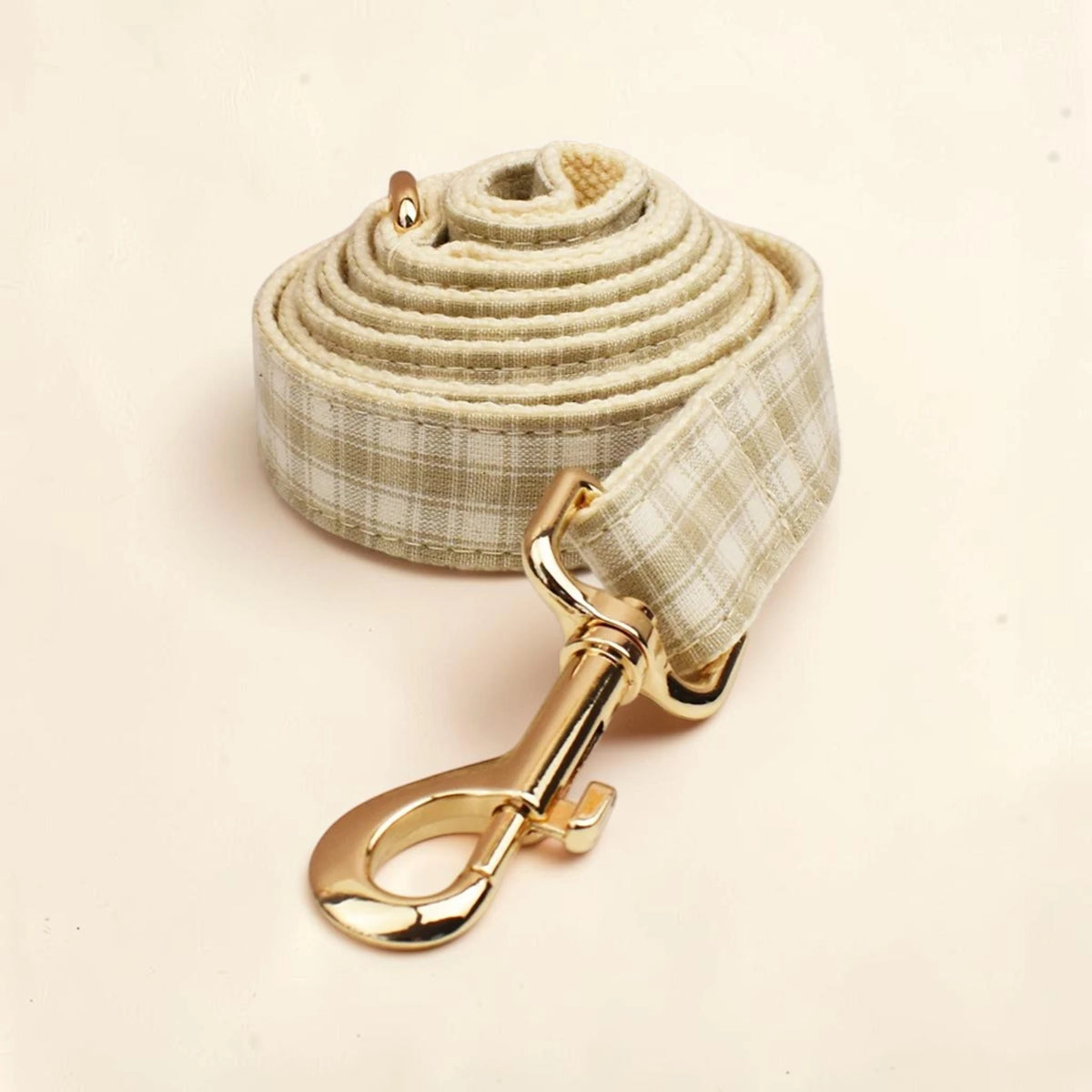 A beige heritage check dog lead with a gold clasp.