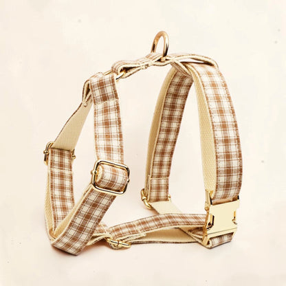 A dog harness with a brown and beige plaid pattern and gold-tone metal hardware.