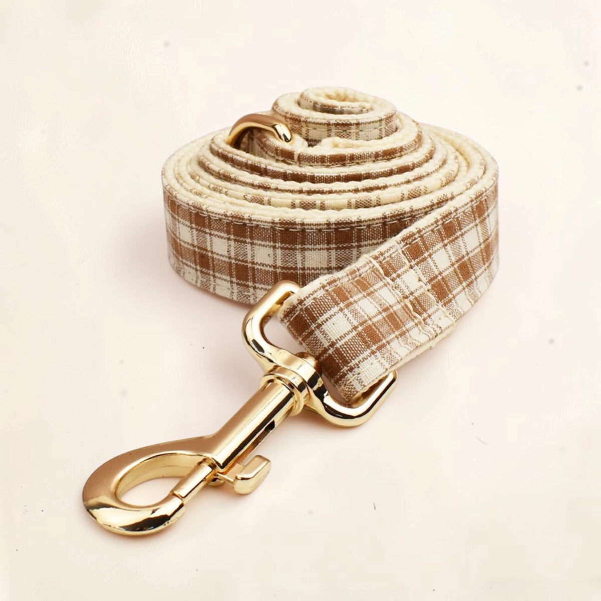 Heritage check dog lead with a brown and beige plaid pattern and shiny gold-tone metal hardware.