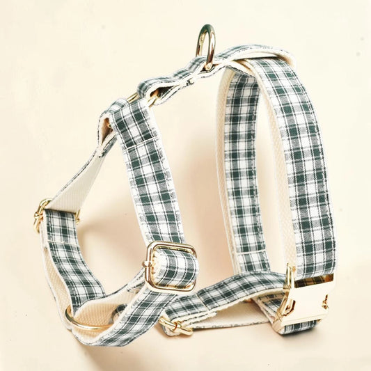 A dog harness with a green and white plaid pattern, featuring cream-colored fabric lining and gold-tone metal hardware.