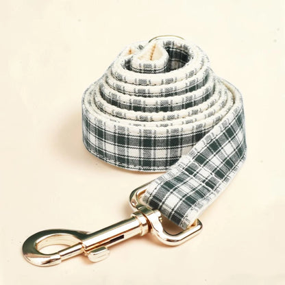 A fabric dog lead with a green and cream plaid pattern and a shiny gold-tone metal clasp.