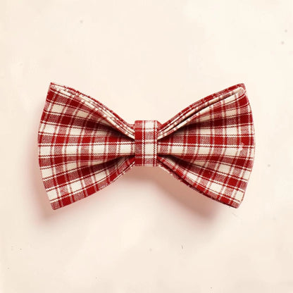 A red and white plaid dog bow tie made of woven fabric.