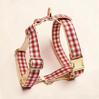 A red and white plaid dog harness with gold-tone metal hardware.