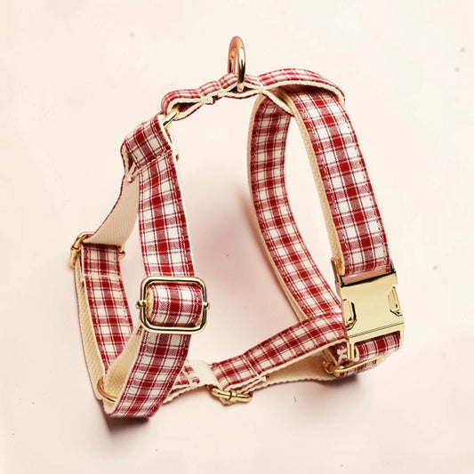 A red and white plaid dog harness with gold-tone metal hardware.