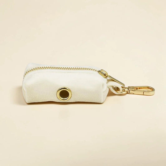 Ivory dog poop bag holder with gold zip and clip on a beige background