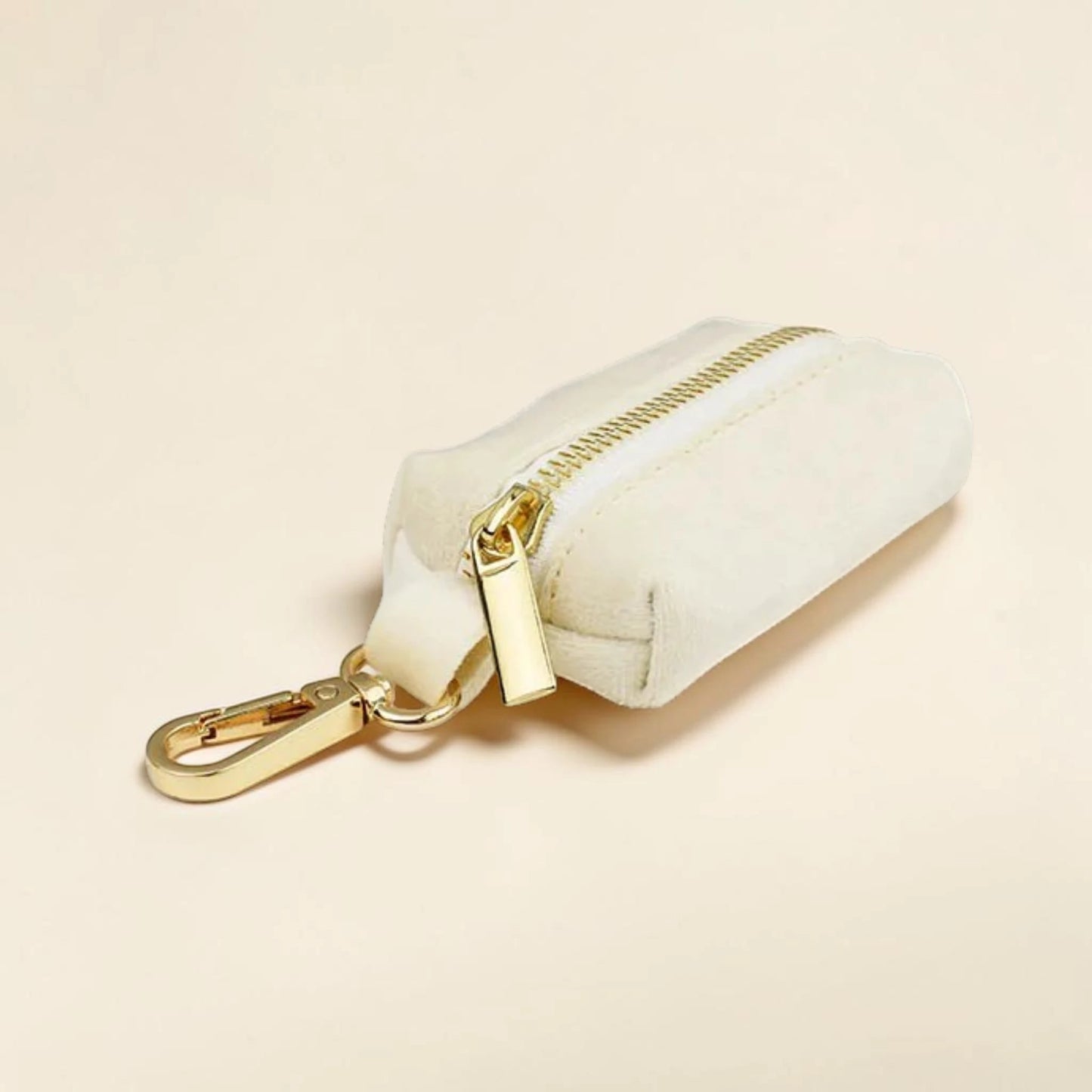 Ivory dog poop bag holder with a gold zip and clip on a beige background