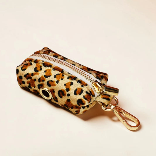 Leopard print dog poop bag holder with gold zip and clip on a beige background