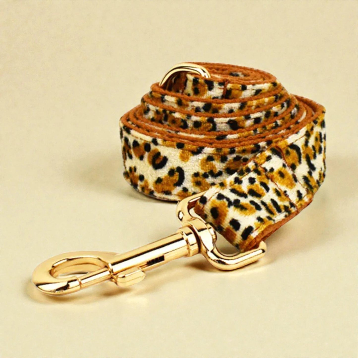 Leopard print dog lead with gold clip on a beige background