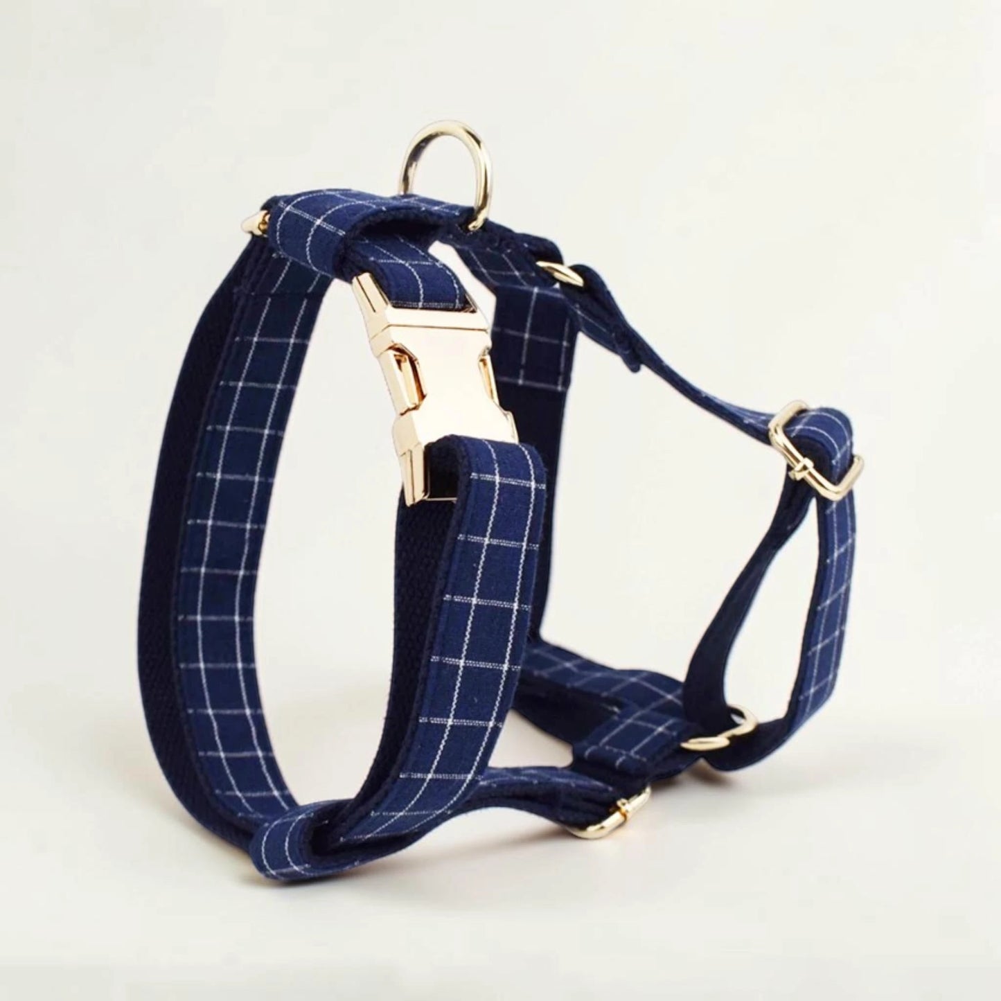 Navy check dog harness with gold hardware on a light background