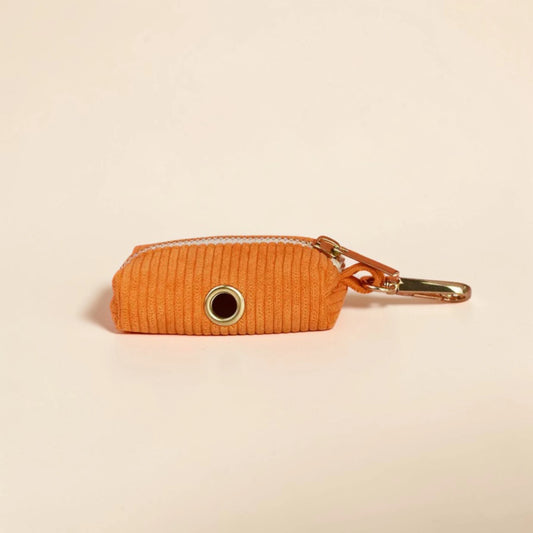 Orange corduroy dog poop bag holder on a beige background