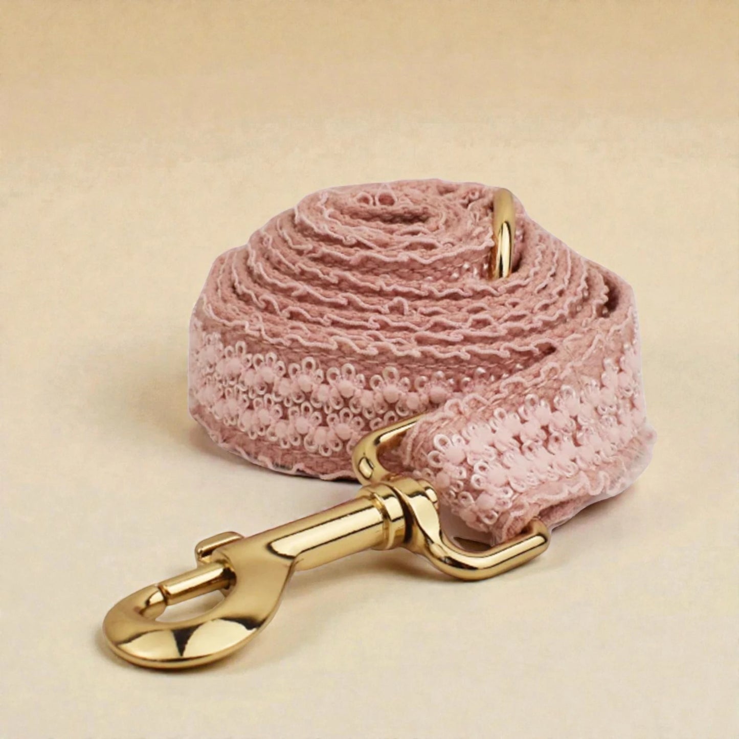 Pink textured dog lead with gold hardware on a beige background