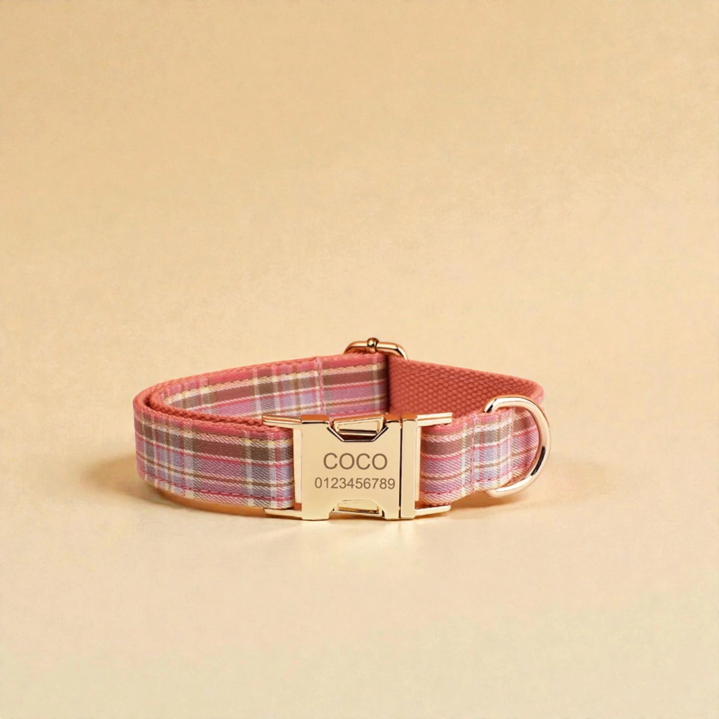 Pink plaid dog collar with a gold personalised buckle on a beige background