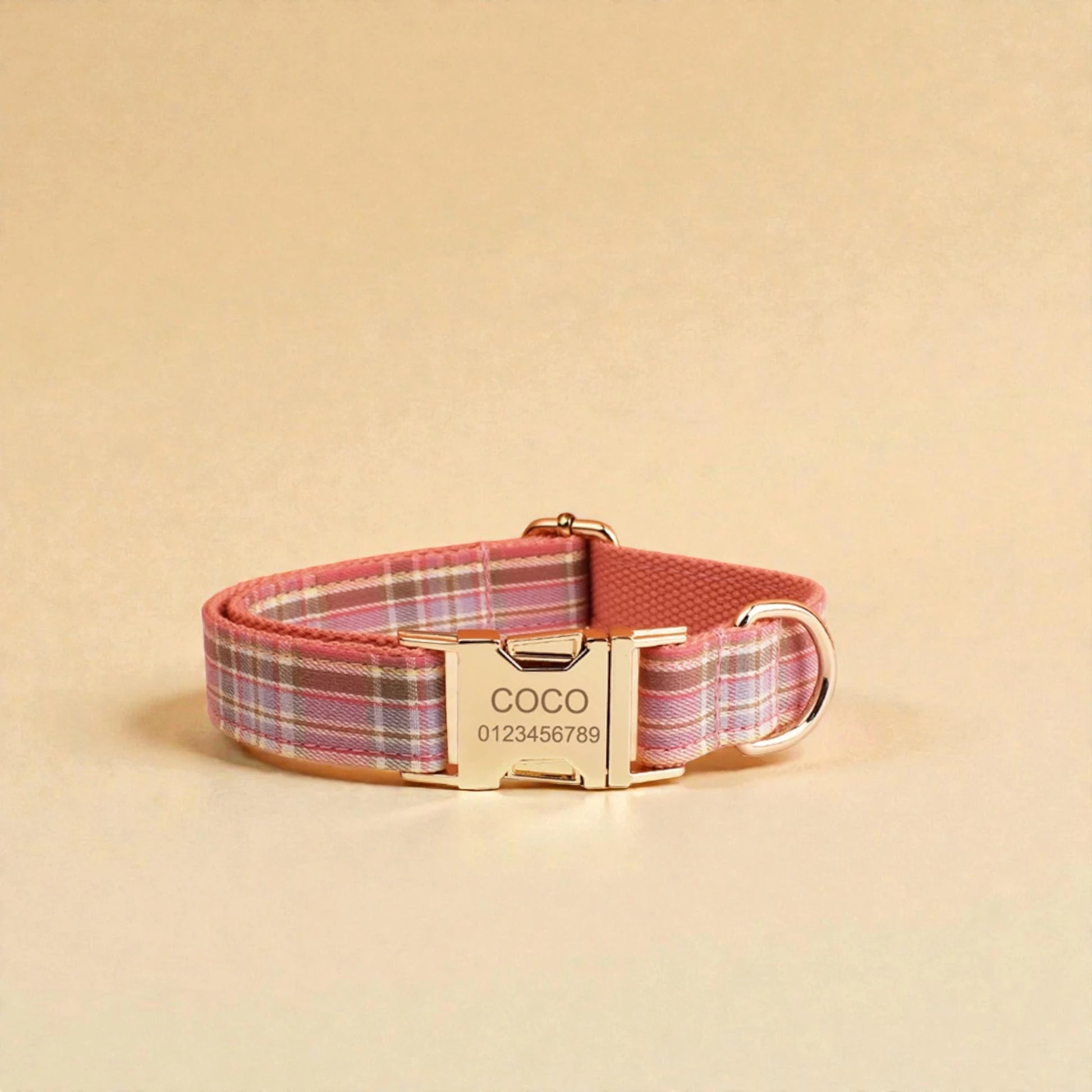 Pink plaid dog collar with a gold personalised buckle on a beige background