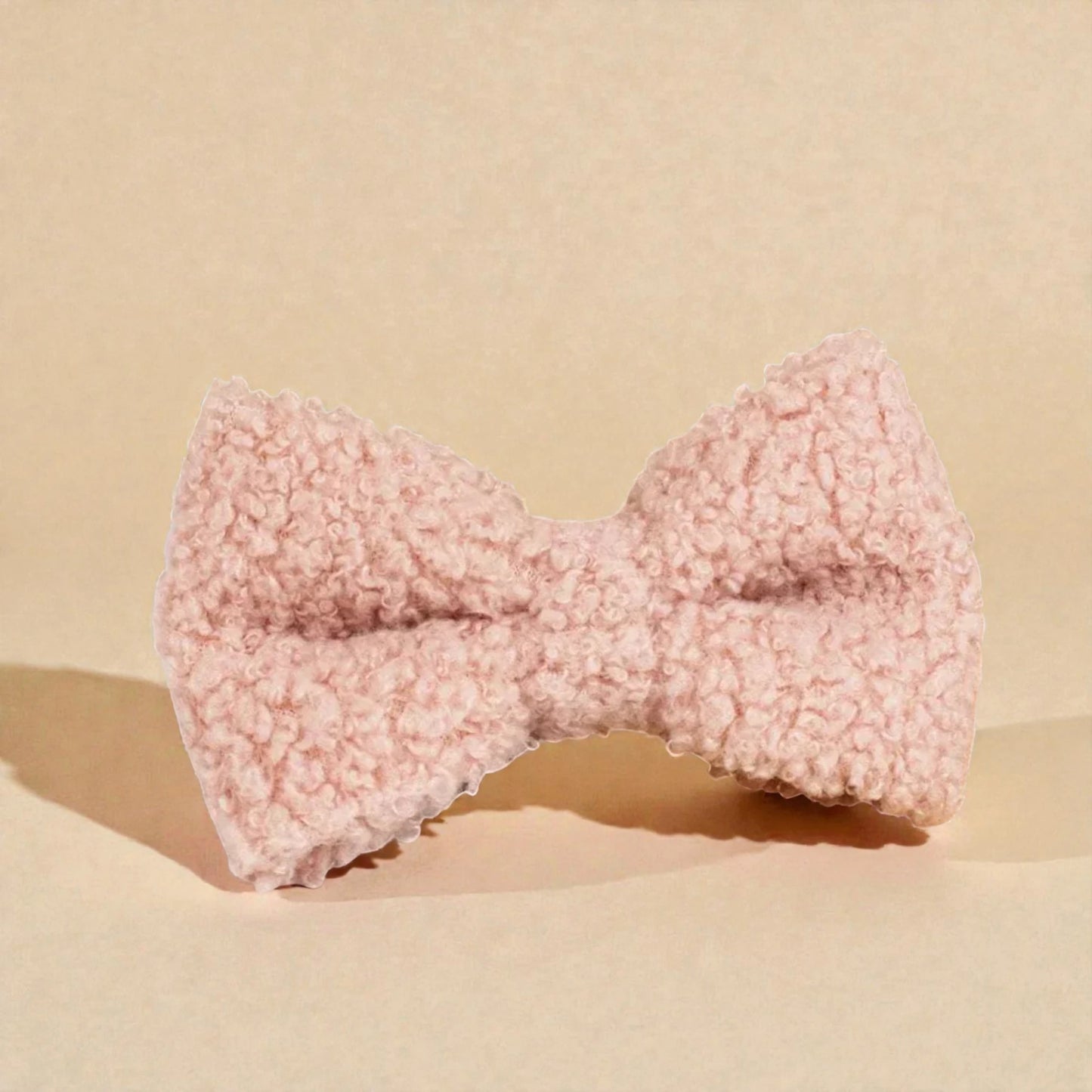 Pink fleece bow on a beige background