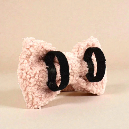 Pink fleece bow with black elastic on a beige background