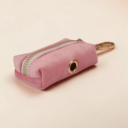 Pink dog poop bag holder with gold zip and clip on a beige background