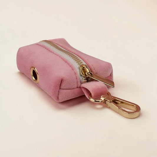 Pink velvet dog poop bag holder with gold zip and clip on a beige background