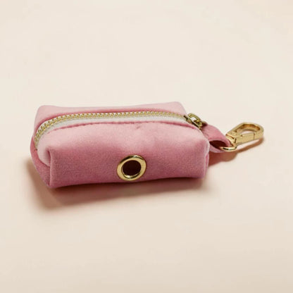Pink velvet dog poop bag holder with gold zip and clip on a beige background