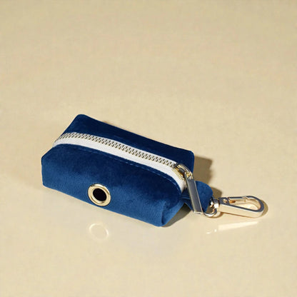Blue velvet dog poop bag holder with a gold zip on a beige background