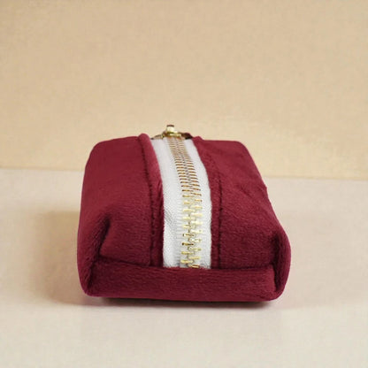 Red dog poop bag holder with a gold zip on a beige background