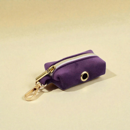 Purple velvet poop bag holder with gold zip and clip on a beige background