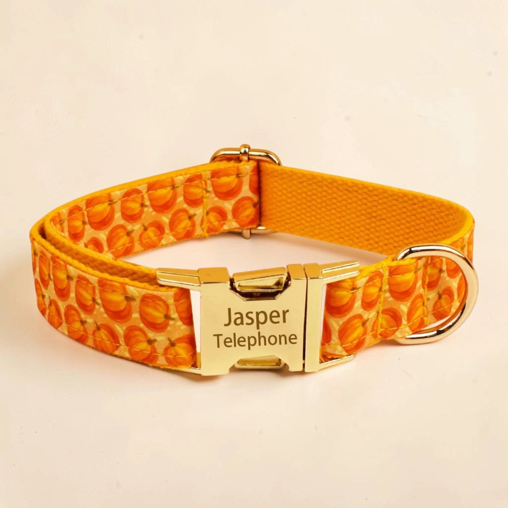 A personalised dog collar featuring a vibrant orange and yellow pumpkin pattern, a gold metal buckle and a gold metal D-ring.
