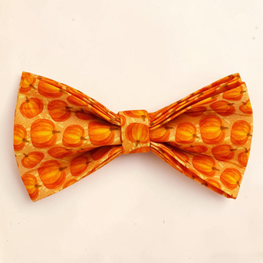 A dog bow tie featuring an all-over pumpkin pattern in shades of orange and yellow.