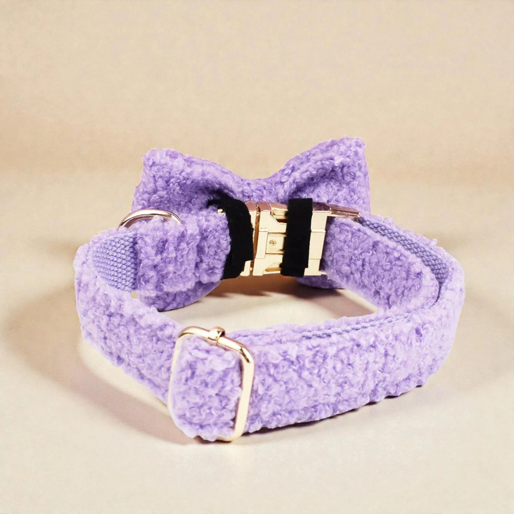 Purple textured dog collar with gold hardware on a beige background