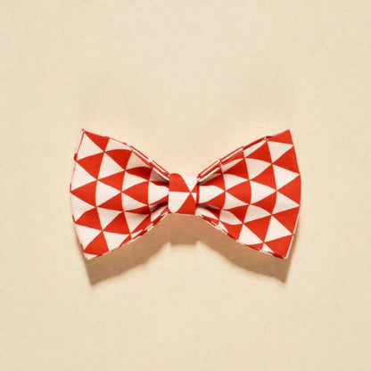 Red and white geometric patterned dog bow tie on a beige background