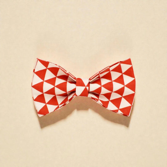 Red and white geometric patterned dog bow tie on a beige background