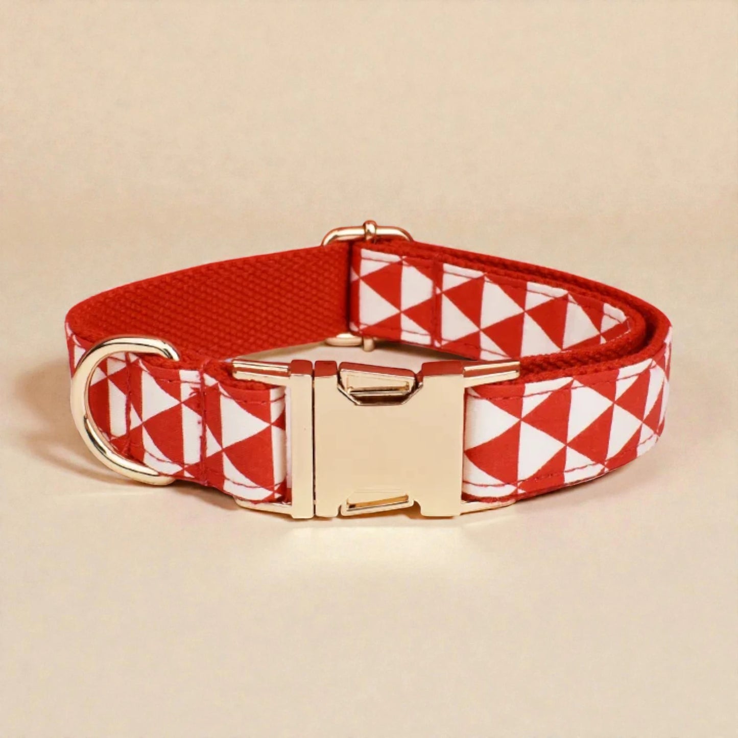 Red and white geometric patterned dog collar with gold buckle on beige background