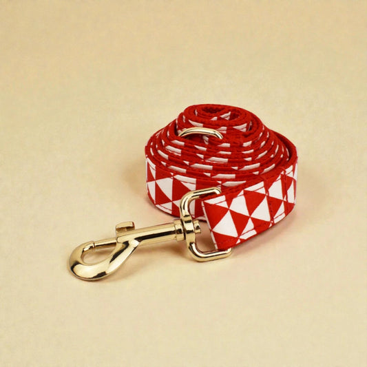 Red and white patterned dog lead with gold clip on beige background